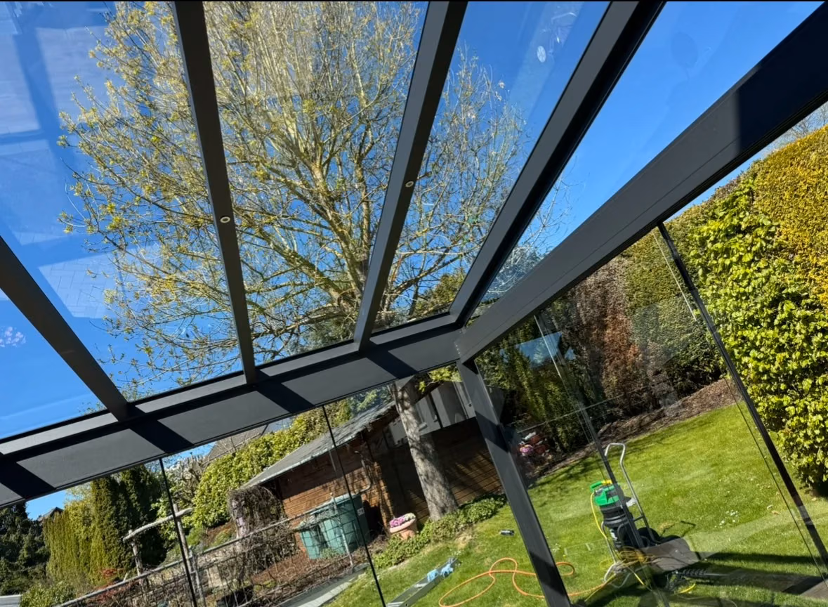 Blick durch eine Glasüberdachung in den Garten